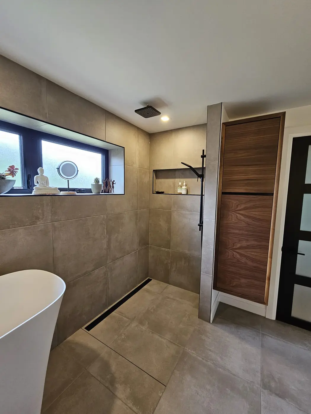 Spa-like bathroom with a freestanding Japanese soaker tub, large-format porcelain tile, and a lit niche window
