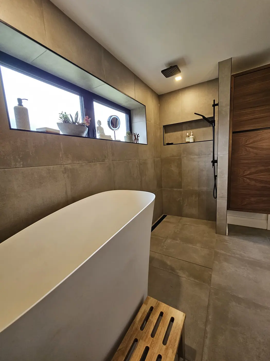 Curbless walk-in wet room with large-format tile, a linear drain, and a black rainfall shower