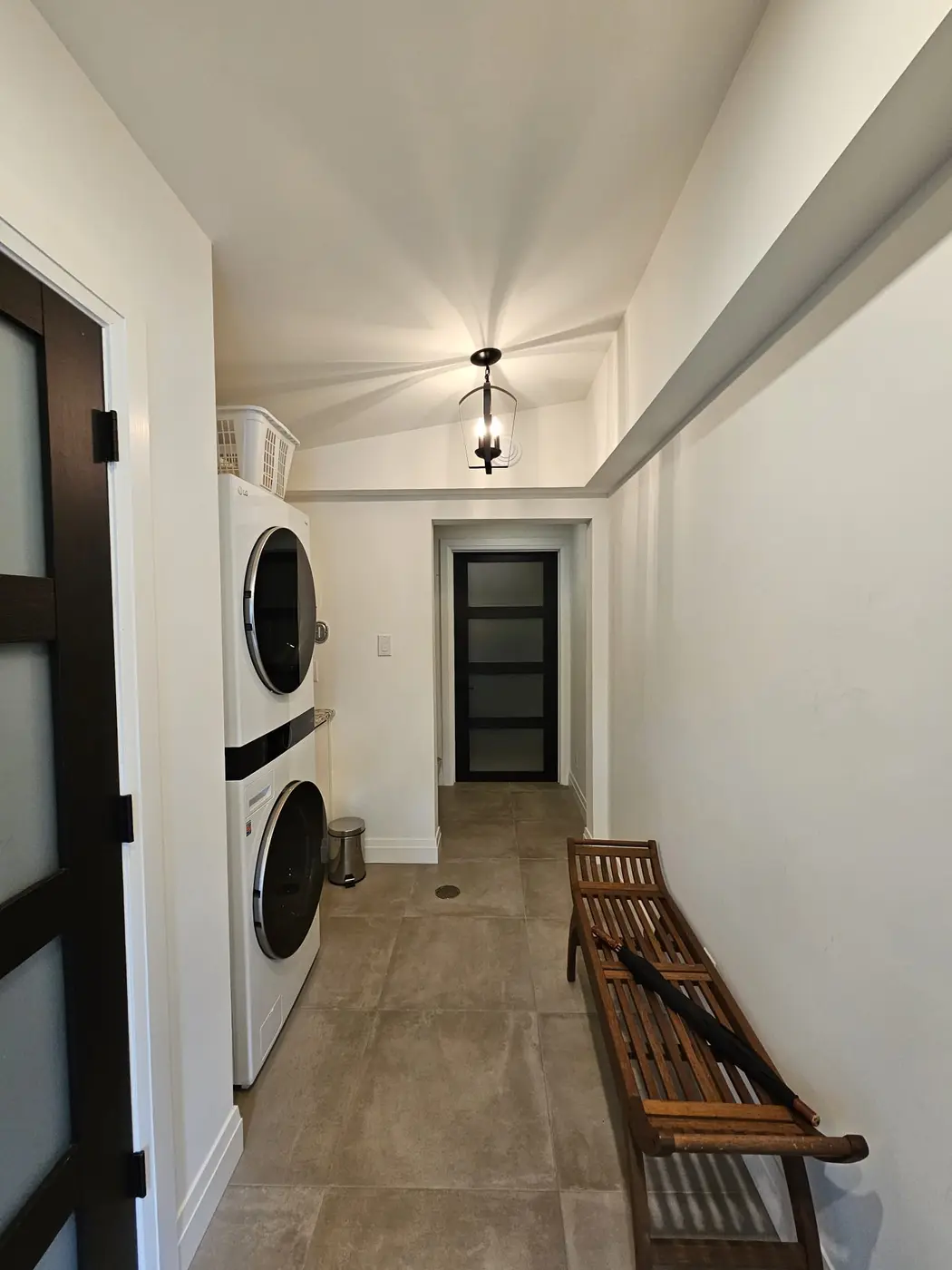 Entry hall with porcelain tile, a glass-paned door, and a stacked laundry pair behind frosted glass doors