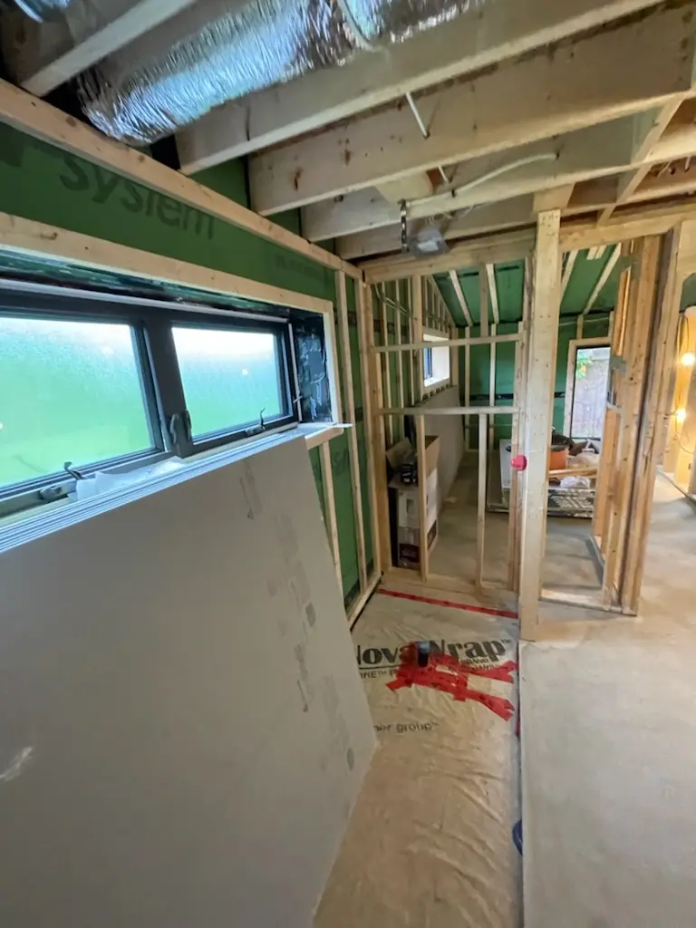 Interior during construction showing mineral wool insulation between studs and HRV ductwork running overhead