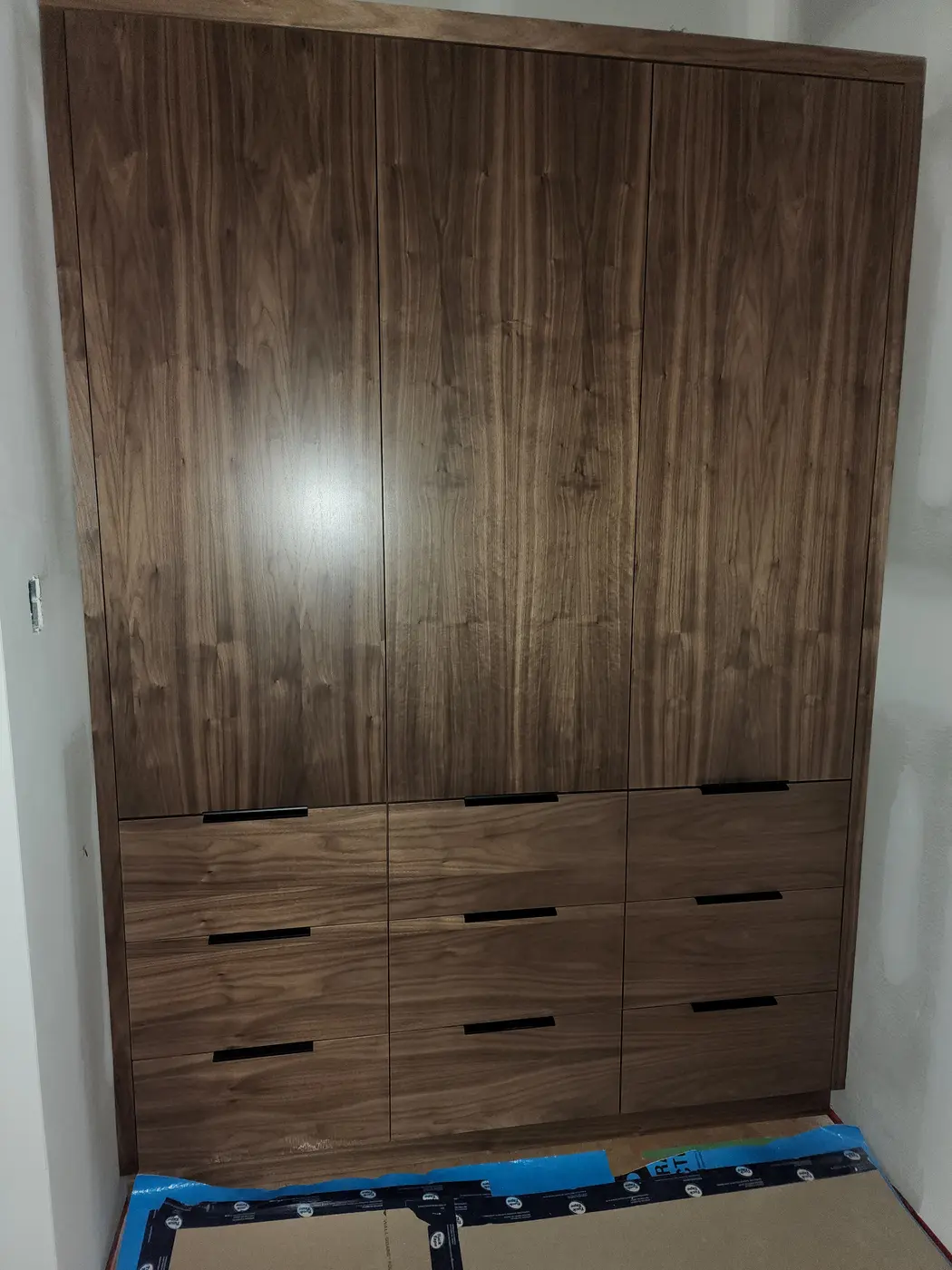 Floor-to-ceiling custom walnut wardrobe with integrated drawers and matched grain, built into the bedroom