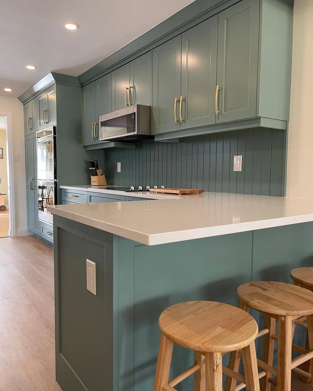 Classic green kitchen with gold handles and matching backsplash in Deer Ridge by Caliber Contracting