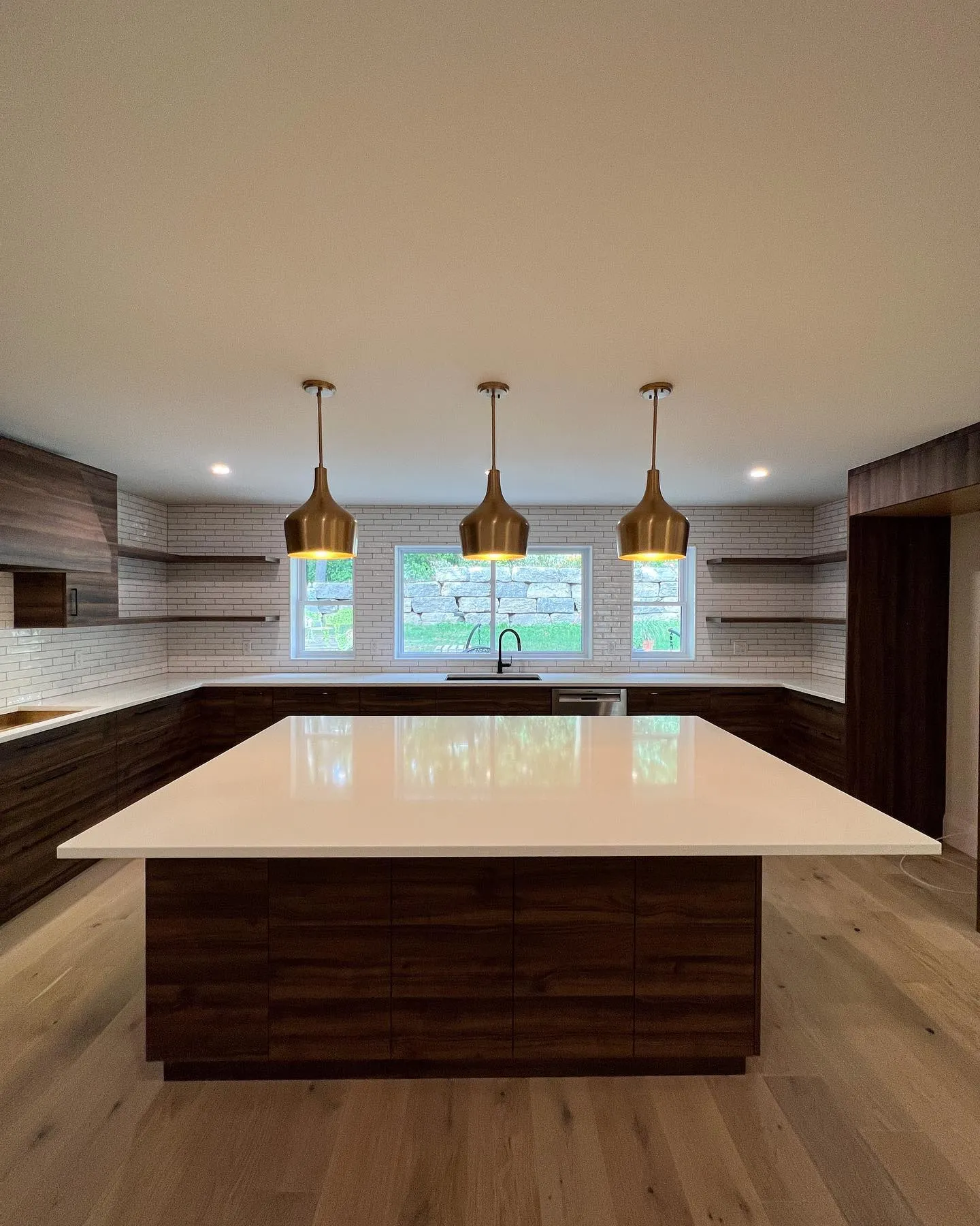 Huge walnut custom kitchen with brass pendants in a new addition in Beechwood by Caliber Contracting