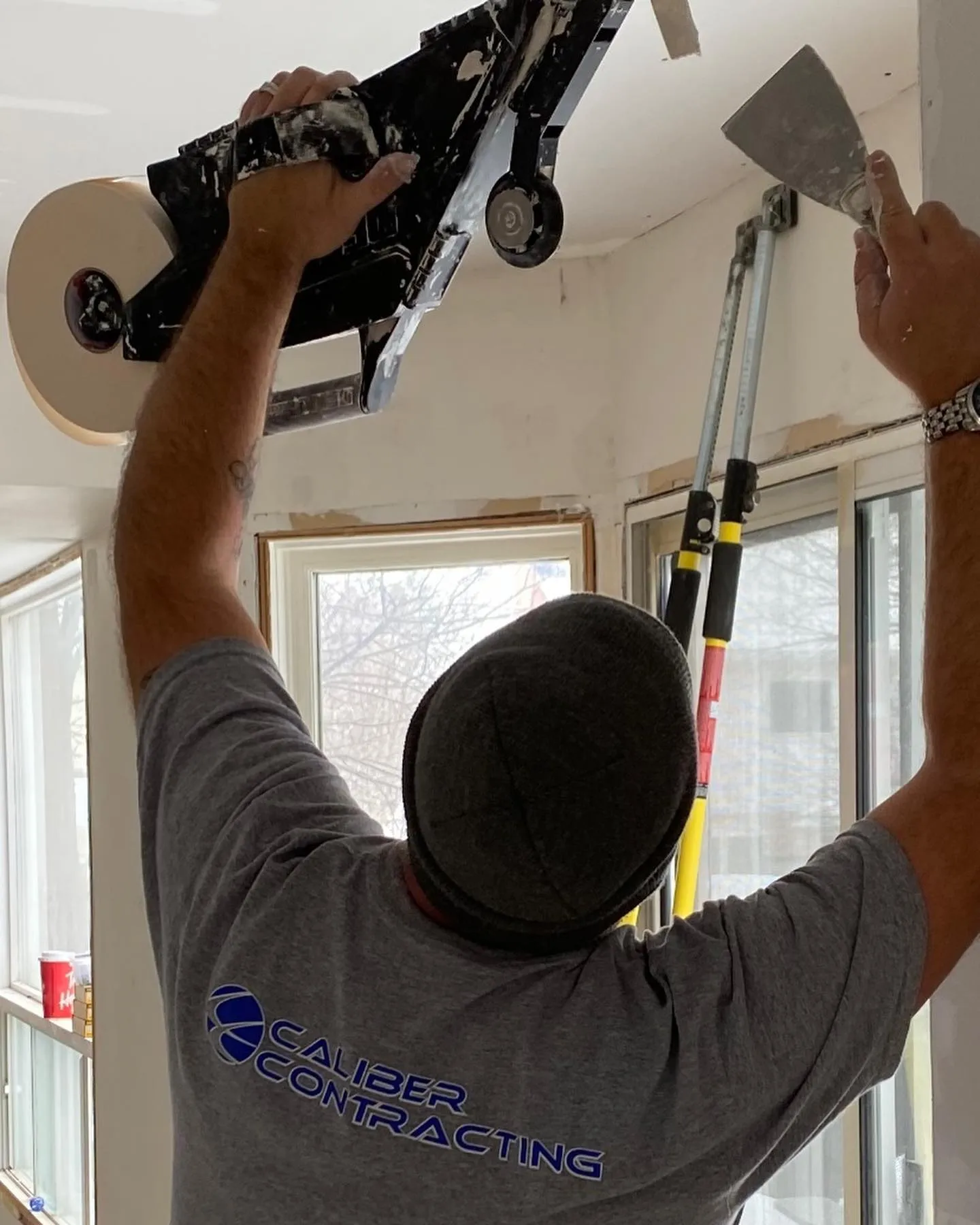 Caliber Contracting team member performing drywall taping